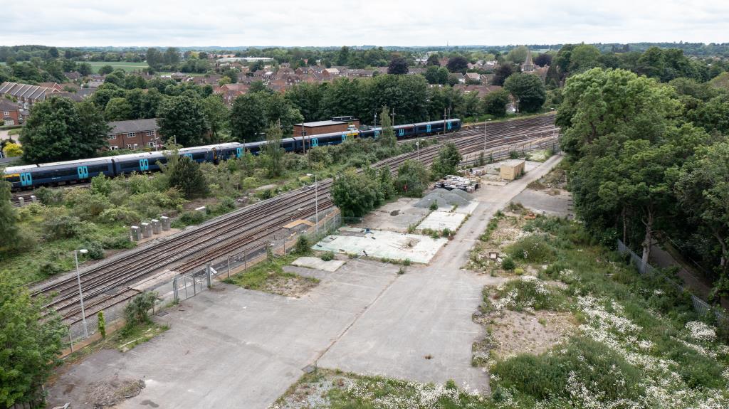 Lot: 114 - LAND WITH PLANNING FOR THIRTY FLATS, TWO BUNGALOWS AND COMMERCIAL SPACE - Drone shot of development site adjacent to railway